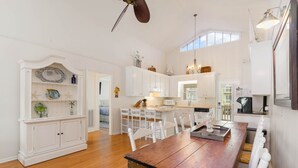 A spacious kitchen with white cabinetry, a wooden dining table, and a ceiling fan. - 4 BDRM CANAL HOUSE WITH LARGE OUTDOOR LIVING SPACE (Ocean Isle Beach)