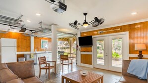 A modern living room with a wooden table, two sofas, and a TV mounted on the wall. - 4 BDRM CANAL HOUSE WITH LARGE OUTDOOR LIVING SPACE (Ocean Isle Beach)