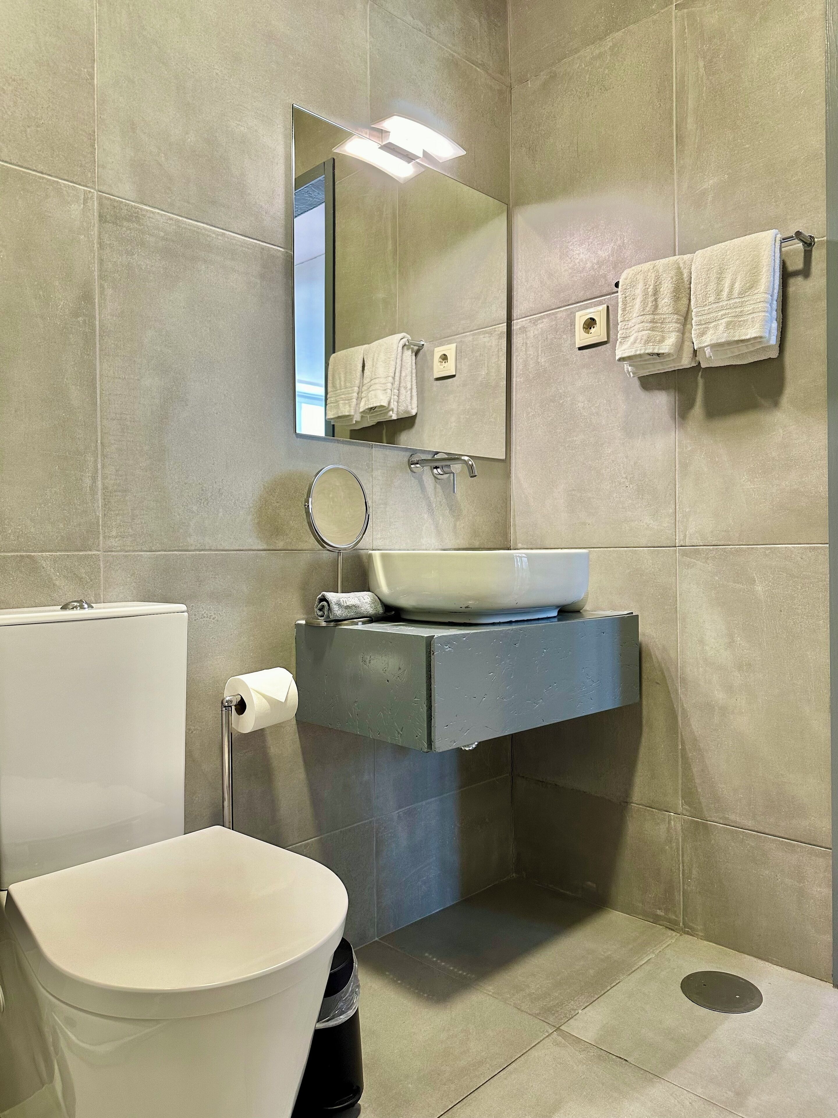 A modern bathroom with a white toilet, a sink with a mirror, and two towels hanging on a towel rack.