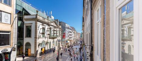 Une rue animée en plein cœur de la ville, bordée de bâtiments historiques, avec un pavé et de nombreux piétons.