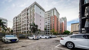 Un immeuble résidentiel à plusieurs étages doté de balcons, un espace de stationnement avec plusieurs voitures et un ciel dégagé.