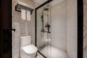 A modern bathroom with a glass-enclosed shower, a white toilet, and a towel rack with two towels. - Nangulee Hotel (Hepu)