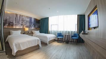 A hotel room with two beds, a desk, two chairs, a TV, and a cityscape painting on the wall.