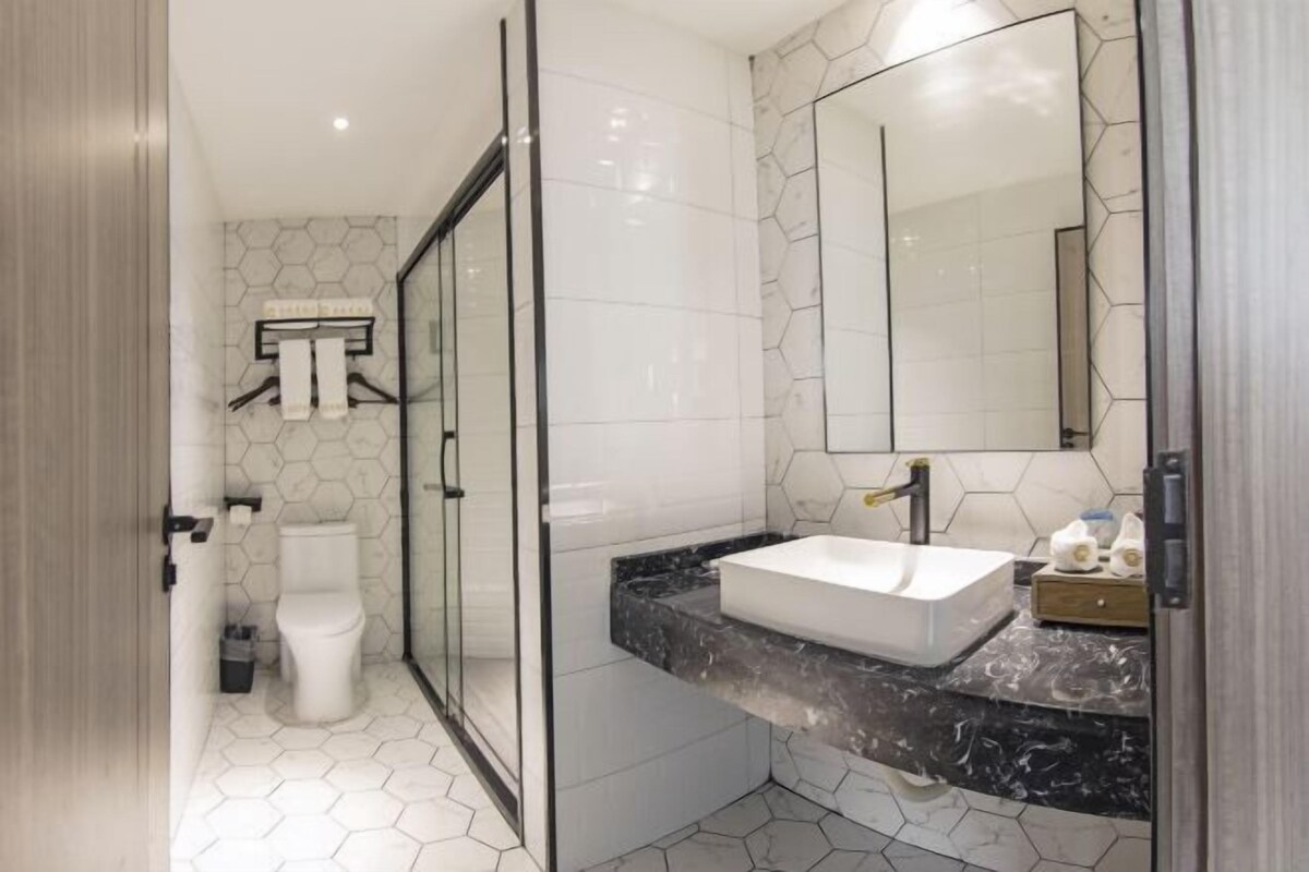 A modern bathroom with a glass shower enclosure, a white toilet, and a marble countertop with a sink.