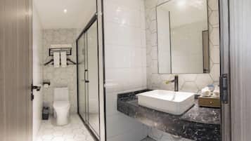A modern bathroom with a glass shower enclosure, a white toilet, and a marble countertop with a sink.