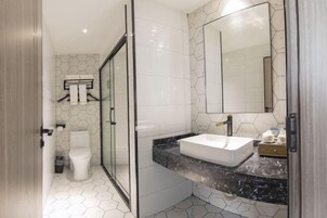 A modern bathroom with a glass shower enclosure, a white toilet, and a marble countertop with a sink.