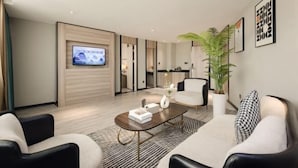 Un salon moderne avec un téléviseur à écran plat, une table basse, deux canapés, une plante en pot et des œuvres d’art encadrées accrochées au mur.