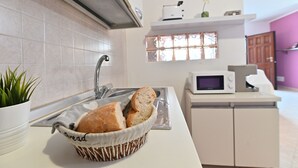 Una cocina con una cesta de pan, un microondas y una planta en maceta.