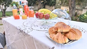 Una mesa con un frutero de vidrio, croissants y botellas de jugo.
