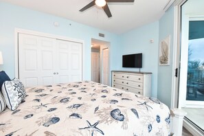Quarto com cama, penteadeira, televisão e porta.