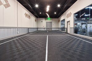 A spacious indoor area with a checkered floor, a green exit sign, and exercise equipment in the background.