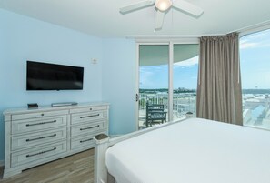 A hotel room with a bed, a TV mounted on the wall, a dresser, and a balcony with a view.