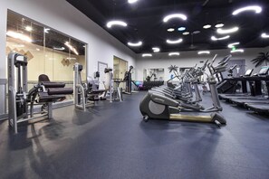 A gym with exercise equipment, a mirrored wall, and a ceiling with circular lights.