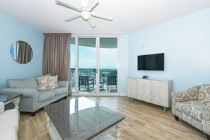 A living room with a sofa, a coffee table, a TV, and a balcony with a view.
