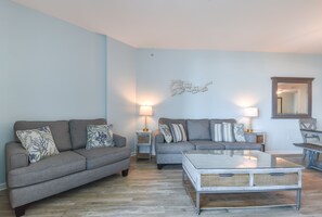 A living room with two grey sofas, a coffee table, and two side tables with lamps.