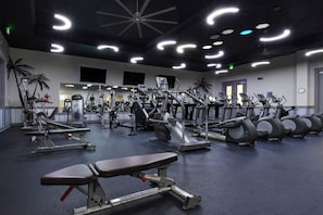 A gym with various exercise equipment, including treadmills, stationary bikes, and weight machines.