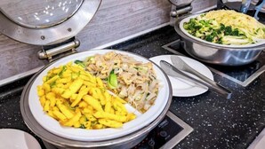 Un buffet proposant divers plats, notamment des nouilles, du riz frit et des légumes.