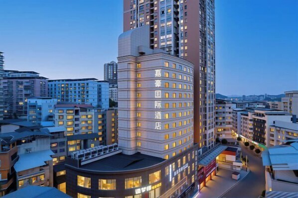A high-rise hotel with multiple floors, a prominent corner entrance, and a well-lit facade.