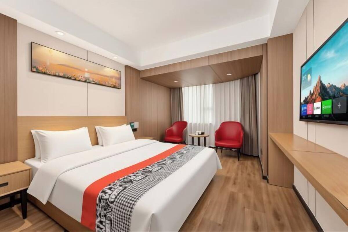 Une chambre d’hôtel avec un grand lit, une télévision, un bureau et une chaise.
