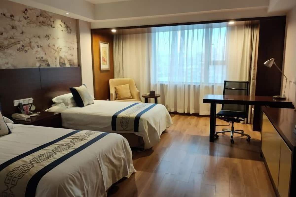 Une chambre d’hôtel avec deux lits, un bureau et une chaise.