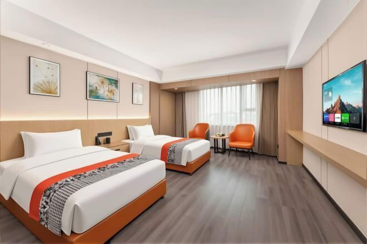 Une chambre d’hôtel avec deux lits, une télévision, un bureau et une chaise.