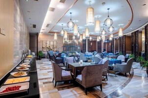 Un moderno vestíbulo de hotel con una amplia mesa de buffet, asientos cómodos e iluminación colgante elegante.