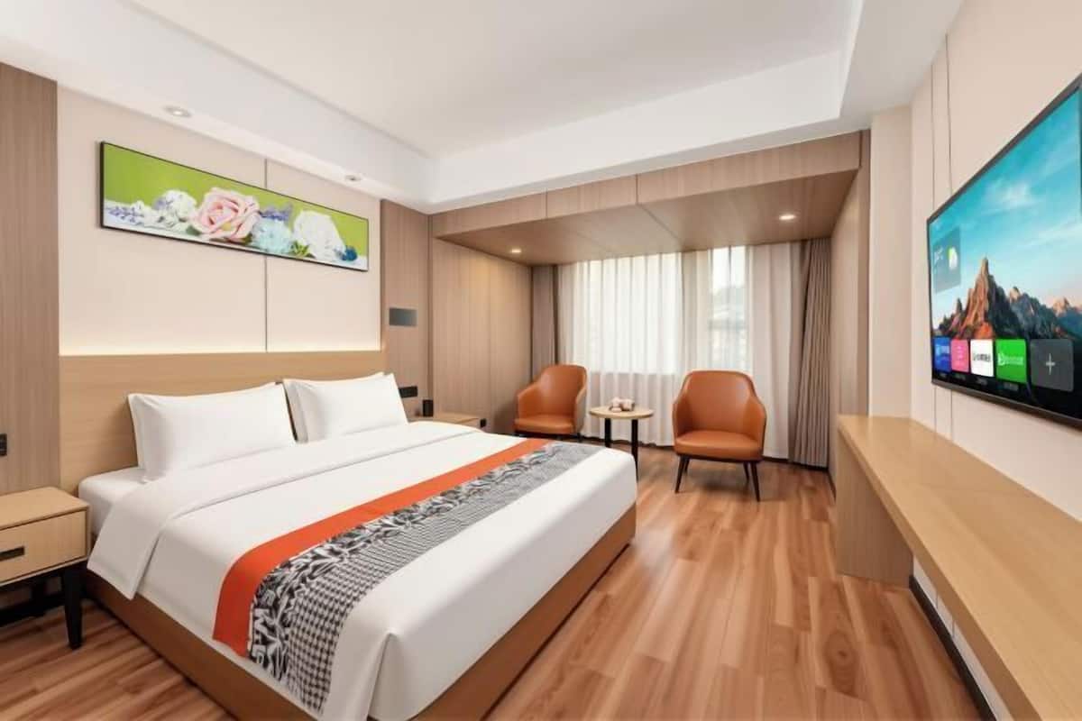 Une chambre d’hôtel avec un lit, une télévision, un bureau et une chaise.
