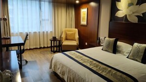 Une chambre d’hôtel avec un grand lit, un bureau, une chaise et une fenêtre avec des rideaux.