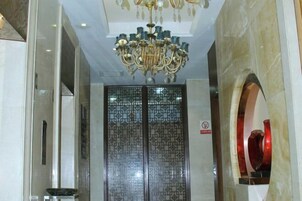 Un interior moderno con una puerta de cristal, una araña y una pared de mármol.