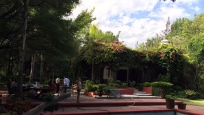 An outdoor patio area with tables and chairs, surrounded by lush greenery and a small water feature. - Escape to Nature and relax in this marvelous Hacienda Home (EL Marques)