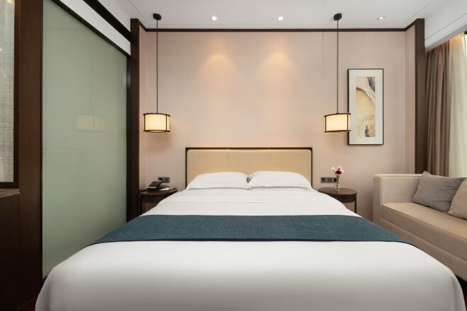 Habitació d'hotel amb un llit gran, taules de nit, una petita taula al costat del llit i un sofà.