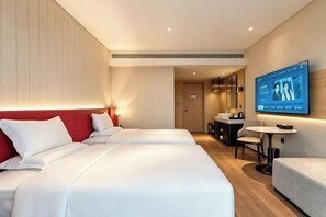 Une chambre d’hôtel avec deux lits, une télévision, un bureau et un canapé.
