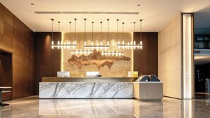 A modern reception area with a marble counter, pendant lighting, and a textured wall design. - Yamei Hotel (Xiangtan Youyi) (Xiangtan)