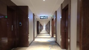 A long, narrow hotel corridor with wooden doors on both sides, a digital sign overhead, and a patterned carpet. - Yamei Hotel (Xiangtan Youyi) (Xiangtan)