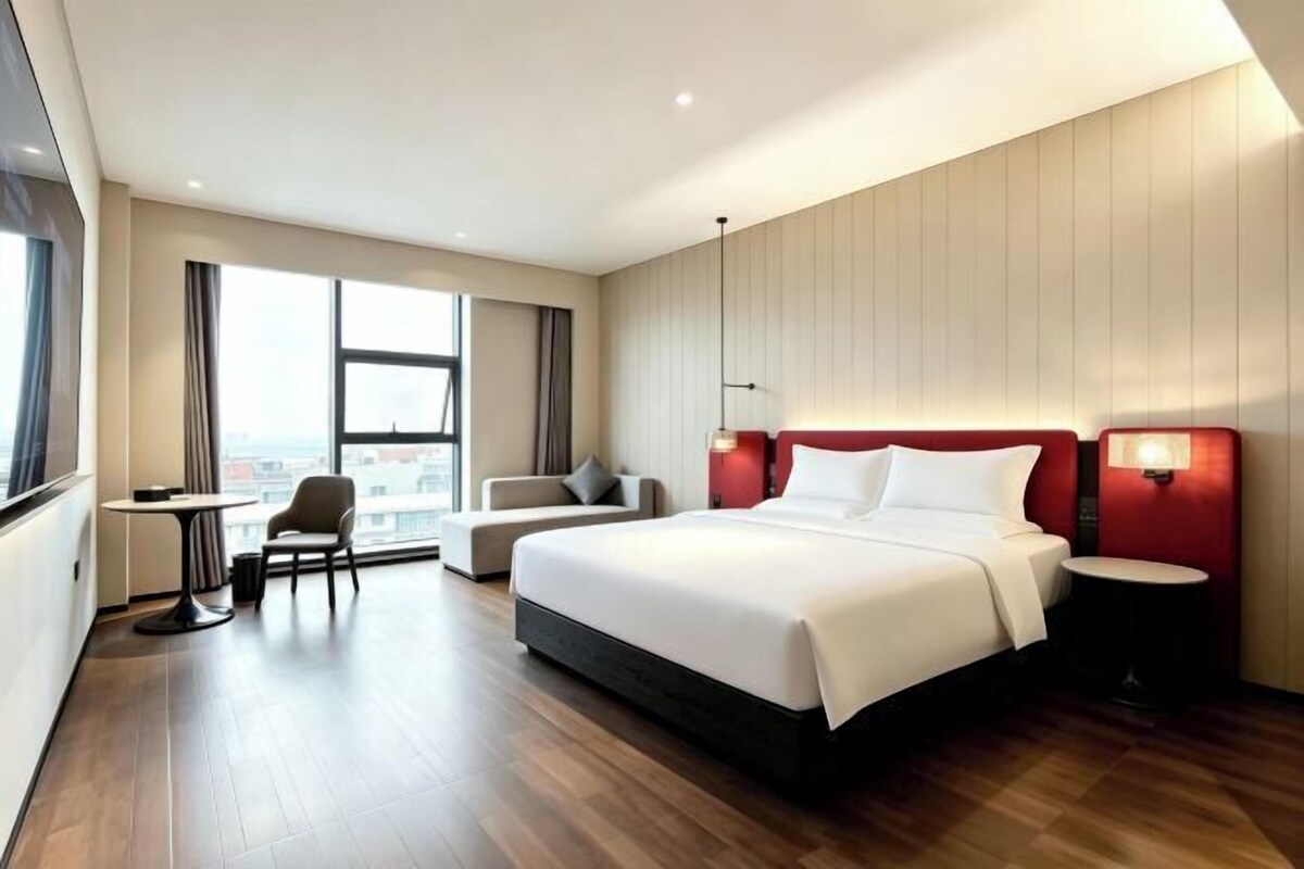 A modern hotel room with a large bed, a desk, and a chair.
