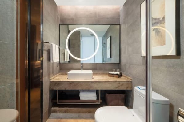 A modern bathroom with a marble vanity, a round mirror with a light, and a toilet. - Yamei Hotel (Xiangtan Youyi) (Xiangtan)