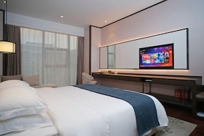 A modern hotel room with a large bed, a flat-screen TV mounted on the wall, and a desk with a chair. - Yamei Hotel (Xiangtan Youyi) (Xiangtan)