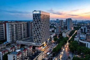 A high-rise building with a prominent sign, surrounded by other buildings and a busy street.