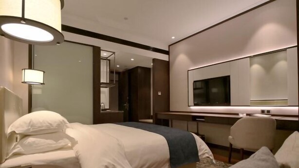A modern hotel room with a large bed, a desk, a chair, and a television. - Yamei Hotel (Xiangtan Youyi) (Xiangtan)