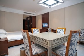 A hotel room with a dining table, four chairs, a television, a bed, and a trash bin. - Yamei Hotel (Xiangtan Youyi) (Xiangtan)