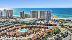 An aerial view of a coastal resort with high-rise buildings, a beach, and a pool area. - Townhome Steps to the Beach · Resort Pool & Courts (Panama City Beach)