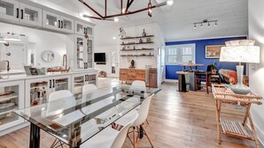 A spacious kitchen with white cabinetry, a large dining table, and a blue accent wall. - Stylish Cozy Cottage in East~10 min. to Broadway (Nashville)