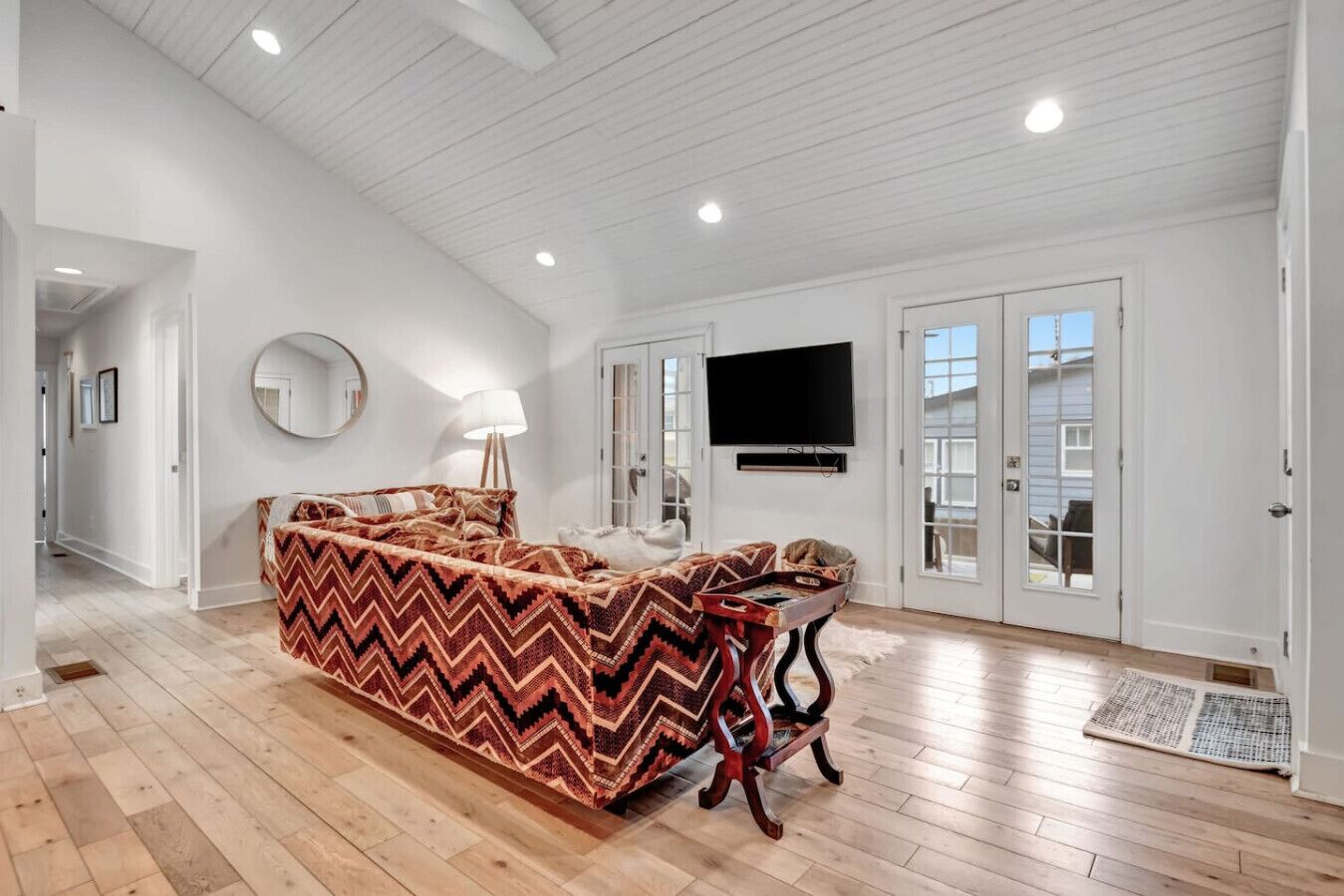 A spacious room with a large bed, a television, and a door leading to a balcony.