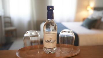 A bottle of Abatilles mineral water on a wooden tray with two glasses.