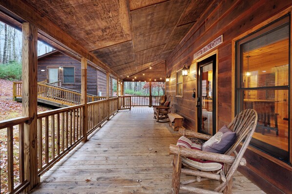 A wooden cabin with a porch, wooden railings, and a bench.