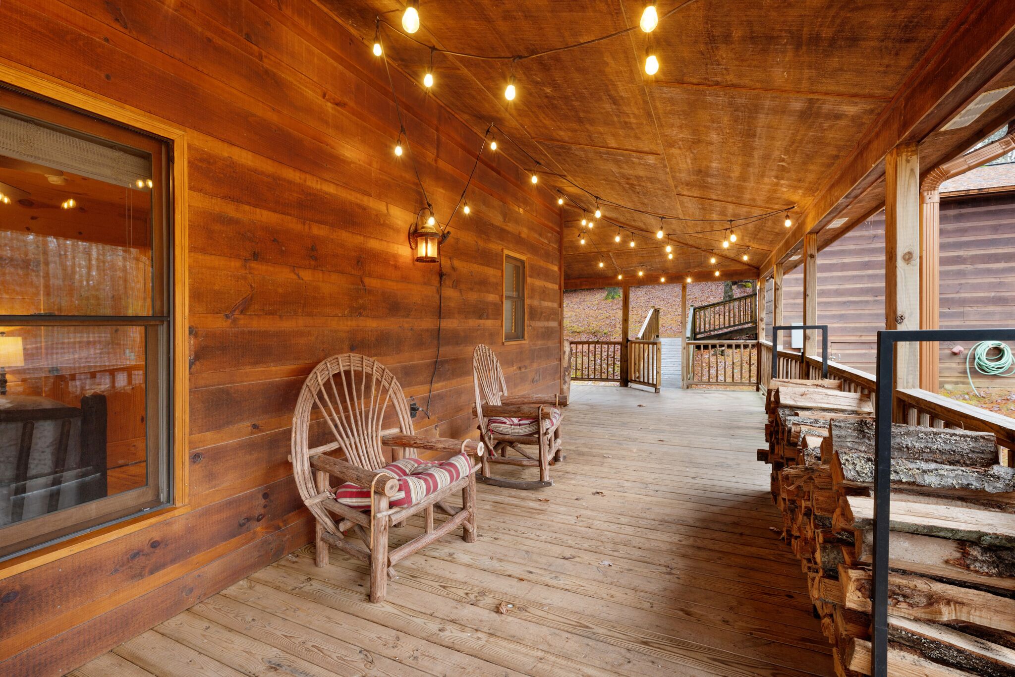 A wooden cabin with a porch, wooden chairs, and a staircase.
