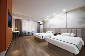 A hotel room with two beds, a desk, chairs, and a TV.