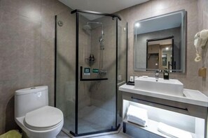 A modern bathroom with a glass-enclosed shower, a toilet, a sink, and a mirror.