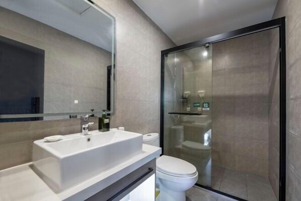 A modern bathroom with a large mirror, a sink, a toilet, and a glass-enclosed shower.