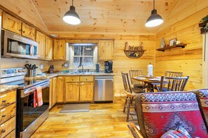 Cozy cabin interior with a fully equipped kitchen, dining area, and warm wooden accents.
